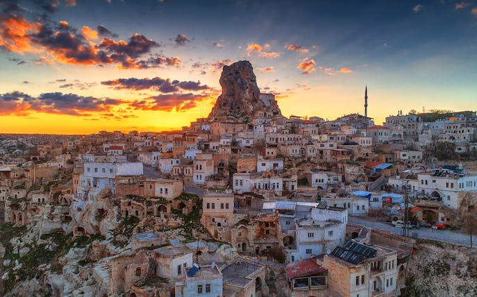 Cappadocia townscape at sunset with rock formations and mosque, Turkey.