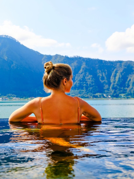 Tourist relaxing in a hot spring with Mount Batur view in Bali.