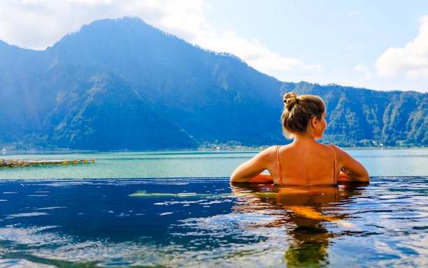 Tourist relaxing in a hot spring with Mount Batur view in Bali.