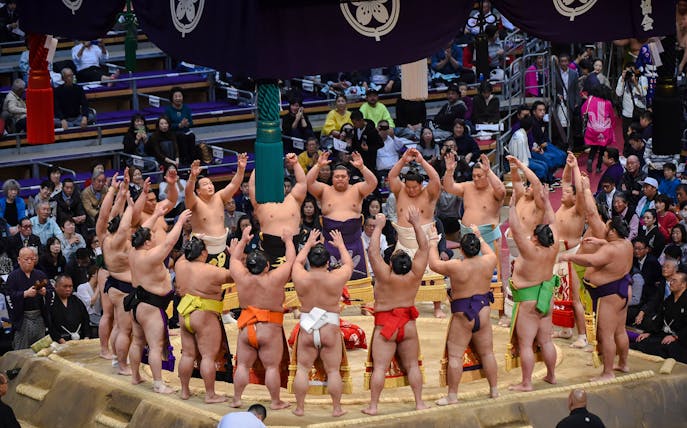 Sumo wrestlers perform a pre-tournament ceremony in a crowded arena in Japan.