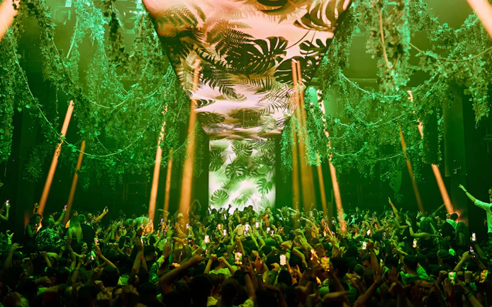 Crowd enjoying Black Coffee performance at Hi Ibiza with vibrant green decor.
