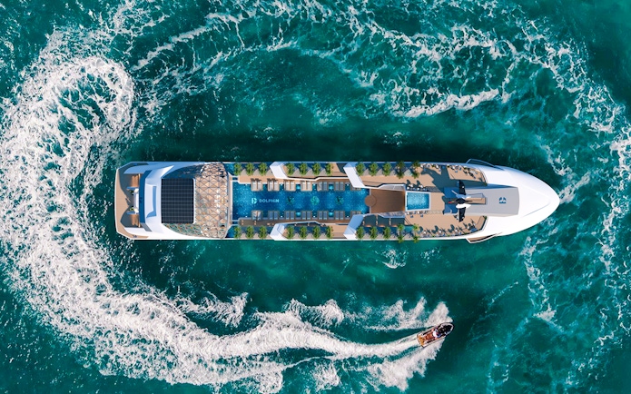 Aerial view of a luxury cruise ship with an infinity pool and sun loungers on deck.