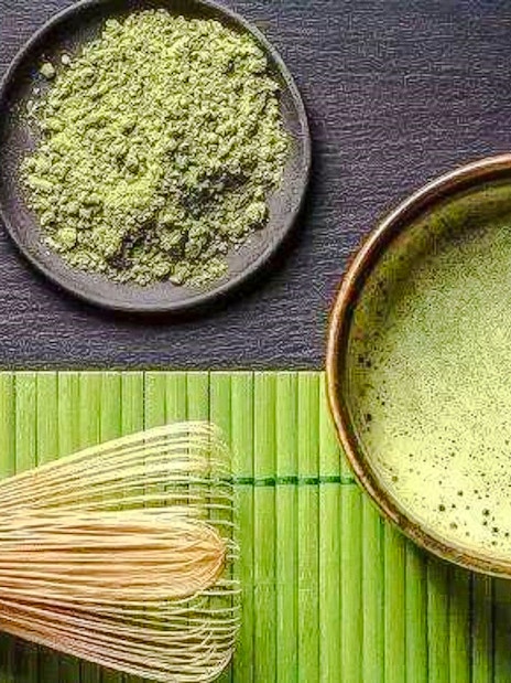 Bamboo whisk, matcha bowl, and powder on a bamboo mat.