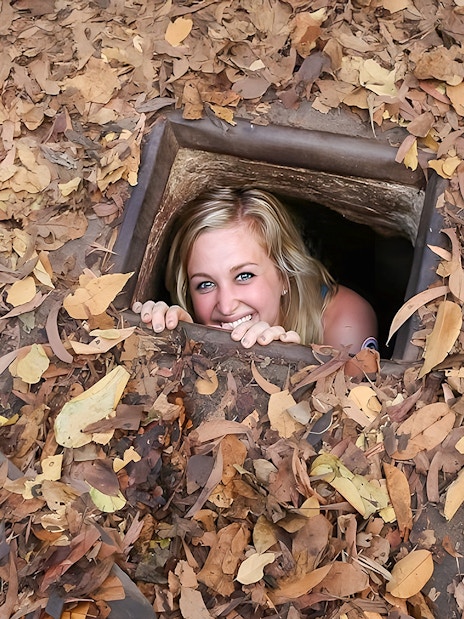 Woman emerging from Cu Chi tunnel in Vietnam.