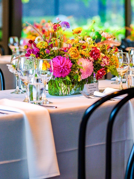 NGV garden restaurant interior with tables set and floral centerpieces.