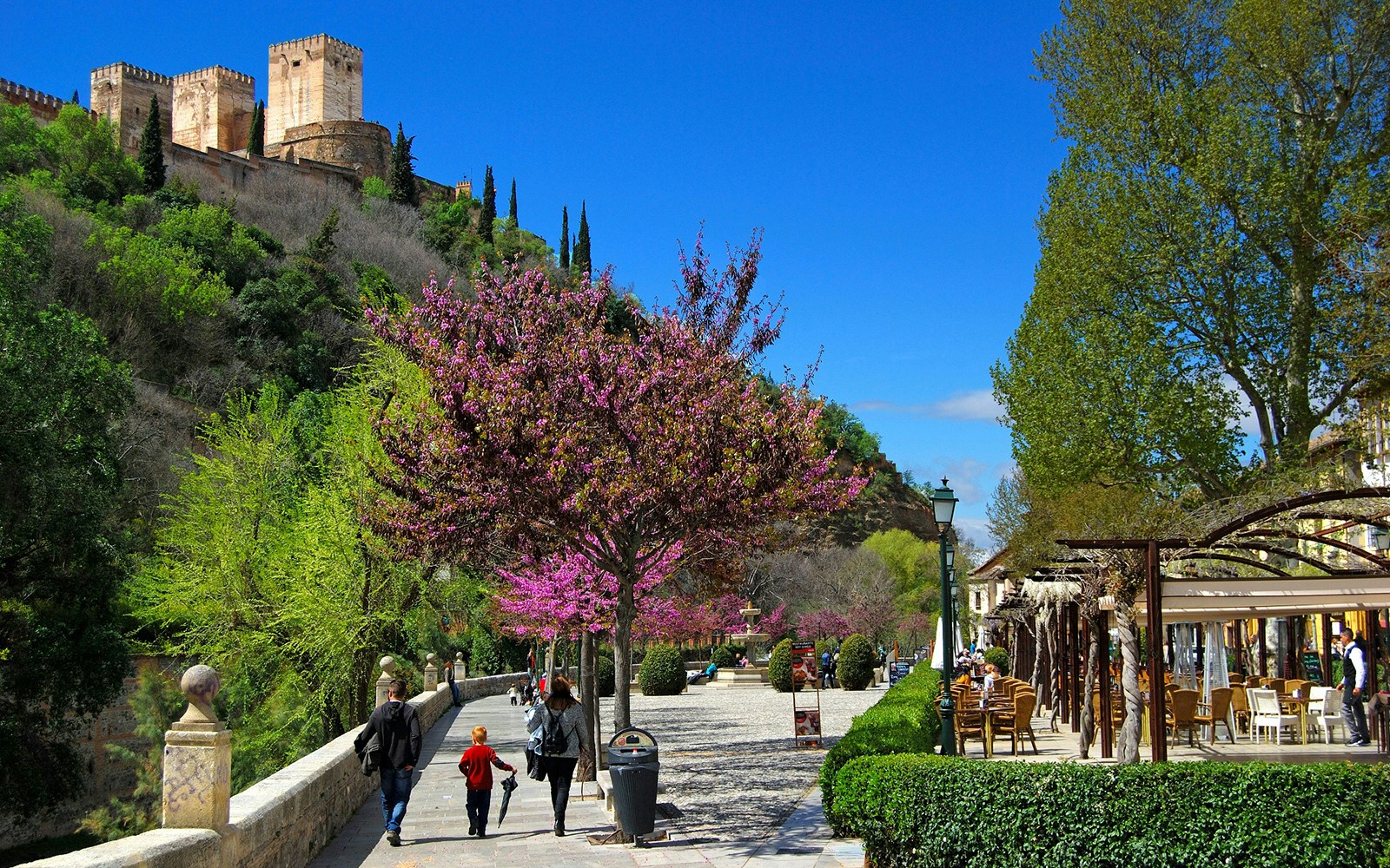 Alhambra view from Albaicin with people walking along a tree-lined path.