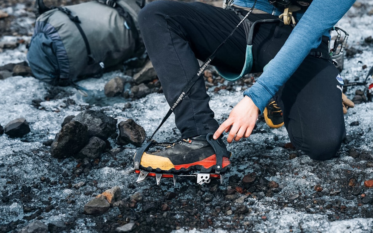 Guest adjusting crampons on glacier tour.