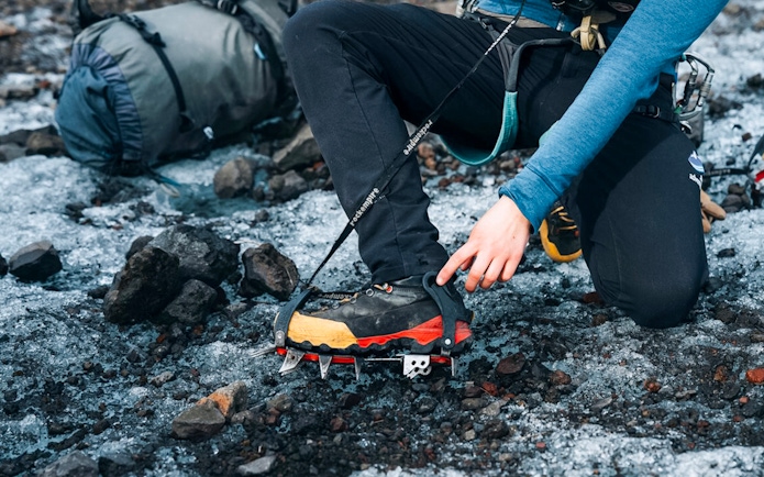 Guest adjusting crampons on glacier tour.