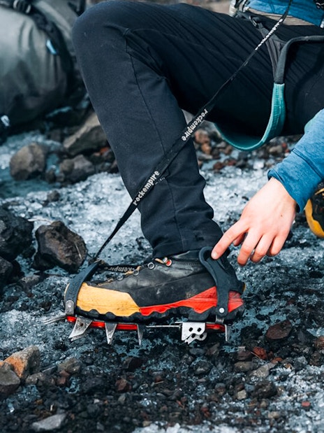 Guest adjusting crampons on glacier tour.