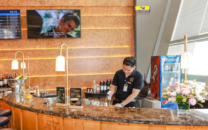 Bartender preparing drinks at SH Premium Lounge bar counter, Noi Bai International Airport, Hanoi.