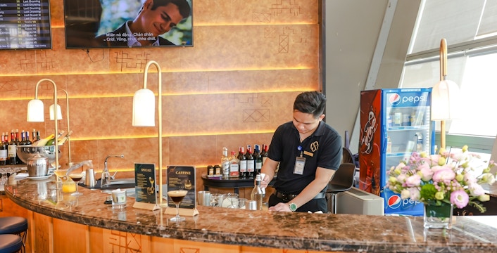 Bartender preparing drinks at SH Premium Lounge bar counter, Noi Bai International Airport, Hanoi.