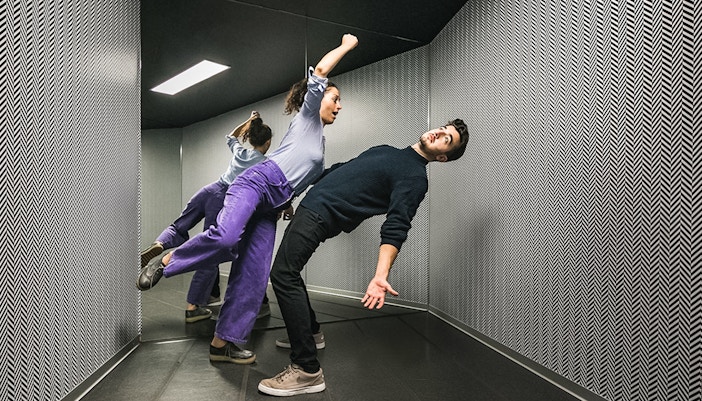 Visitors experiencing the Illuseum Berlin's anti-gravity room with tilted floors and walls.