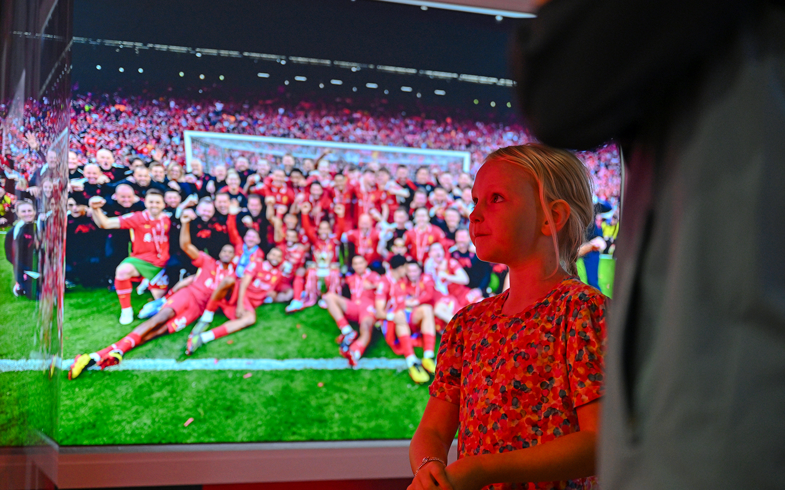 Child observing Liverpool FC team photo at stadium tour.