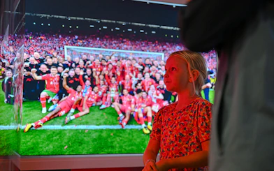 Child observing Liverpool FC team photo at stadium tour.
