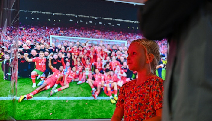 Child observing Liverpool FC team photo at stadium tour.