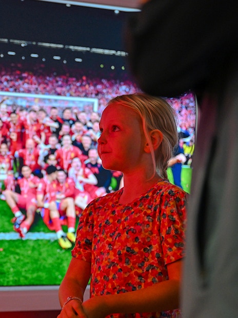 Child observing Liverpool FC team photo at stadium tour.