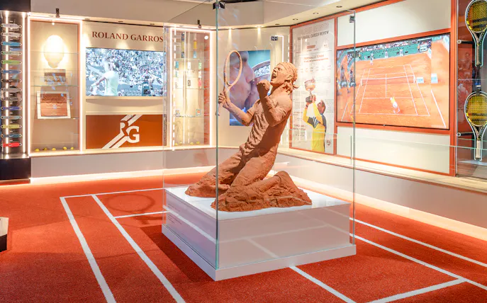 Clay sculpture of a tennis player at Rafa Nadal Museum Xperience, featuring Roland Garros memorabilia.