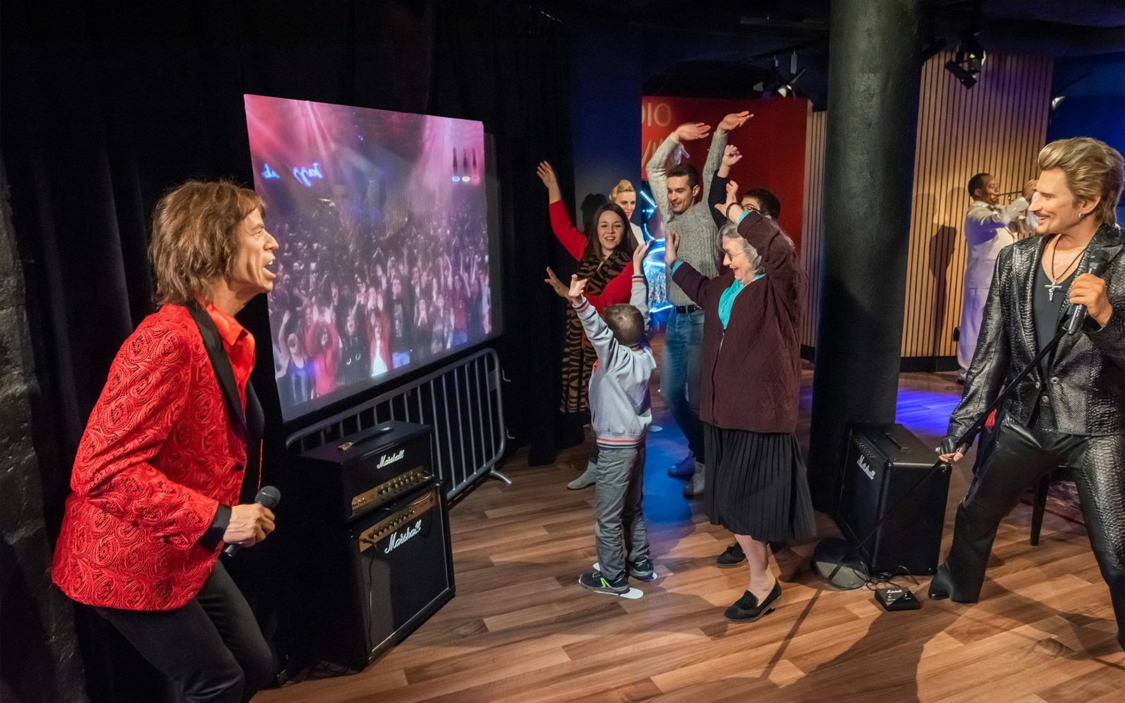 Visitors interacting with music icon wax figures at Grévin Museum, Paris.