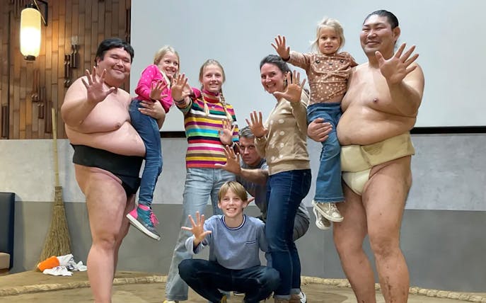 Group posing with sumo wrestlers in Tokyo during Sumo Experience tour.
