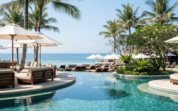Finn's Beach Club poolside with ocean view and palm trees in Bali.