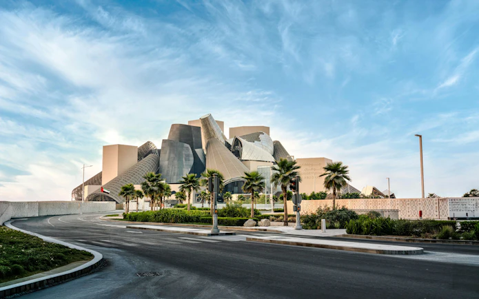 Guggenheim Museum Abu Dhabi with unique architectural design and palm trees in foreground.