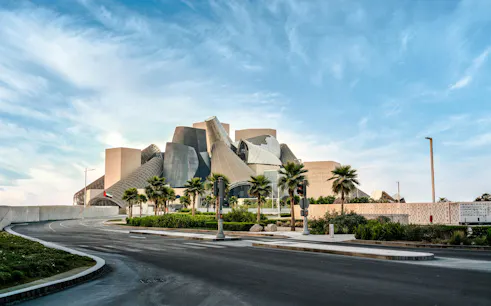 Guggenheim Museum Abu Dhabi with unique architectural design and palm trees in foreground.