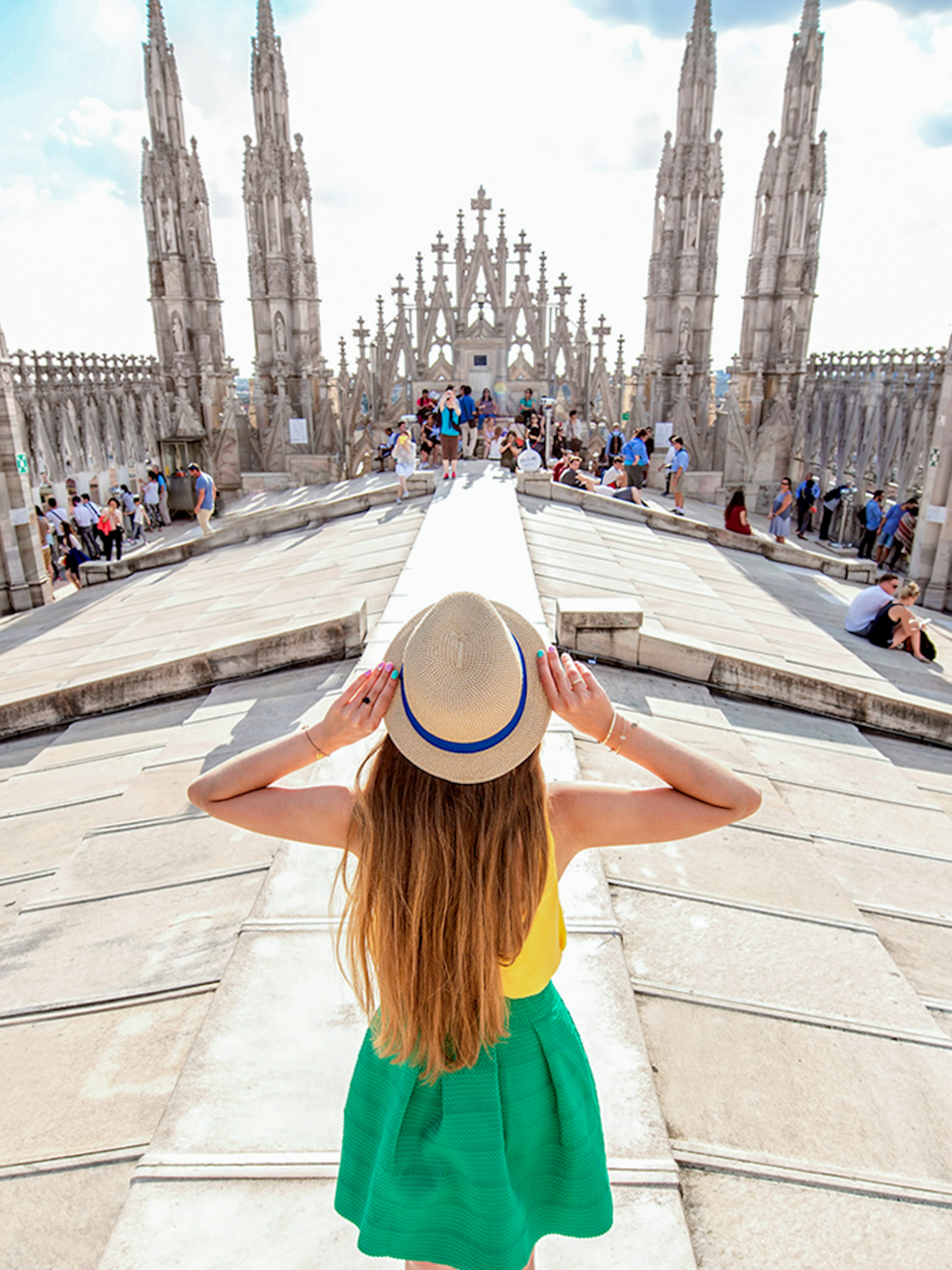 Girl on Milan Duomo rooftop terrace with spires in view.