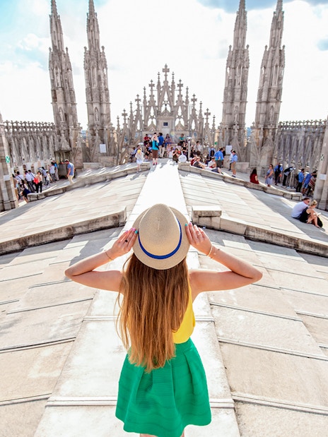 Girl on Milan Duomo rooftop terrace with spires in view.