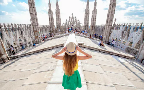 Girl on Milan Duomo rooftop terrace with spires in view.