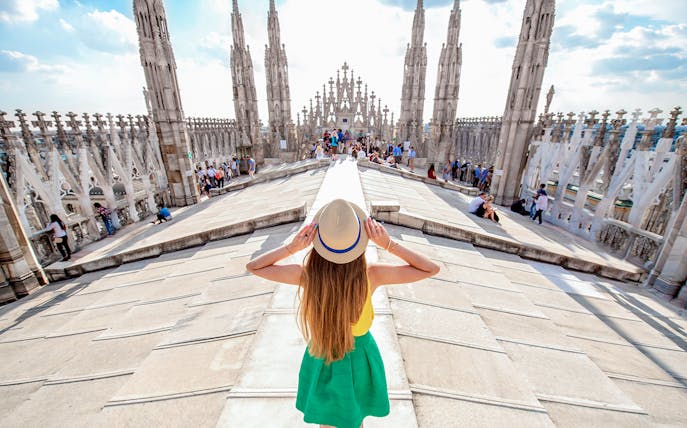 Girl on Milan Duomo rooftop terrace with spires in view.