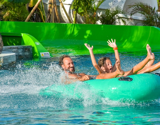 Father and son sliding in a water tube at Waterbom Bali water park, Indonesia.