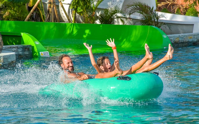 Father and son enjoying a water slide on a tube at Waterbom Bali water park.