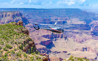 Helicopter flying over Grand Canyon South Rim with expansive canyon views.