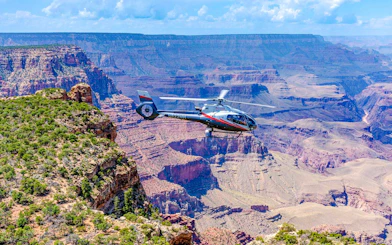 Helicopter flying over Grand Canyon South Rim with expansive canyon views.