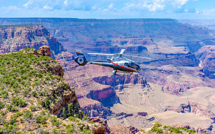 Helicopter flying over Grand Canyon South Rim with expansive canyon views.