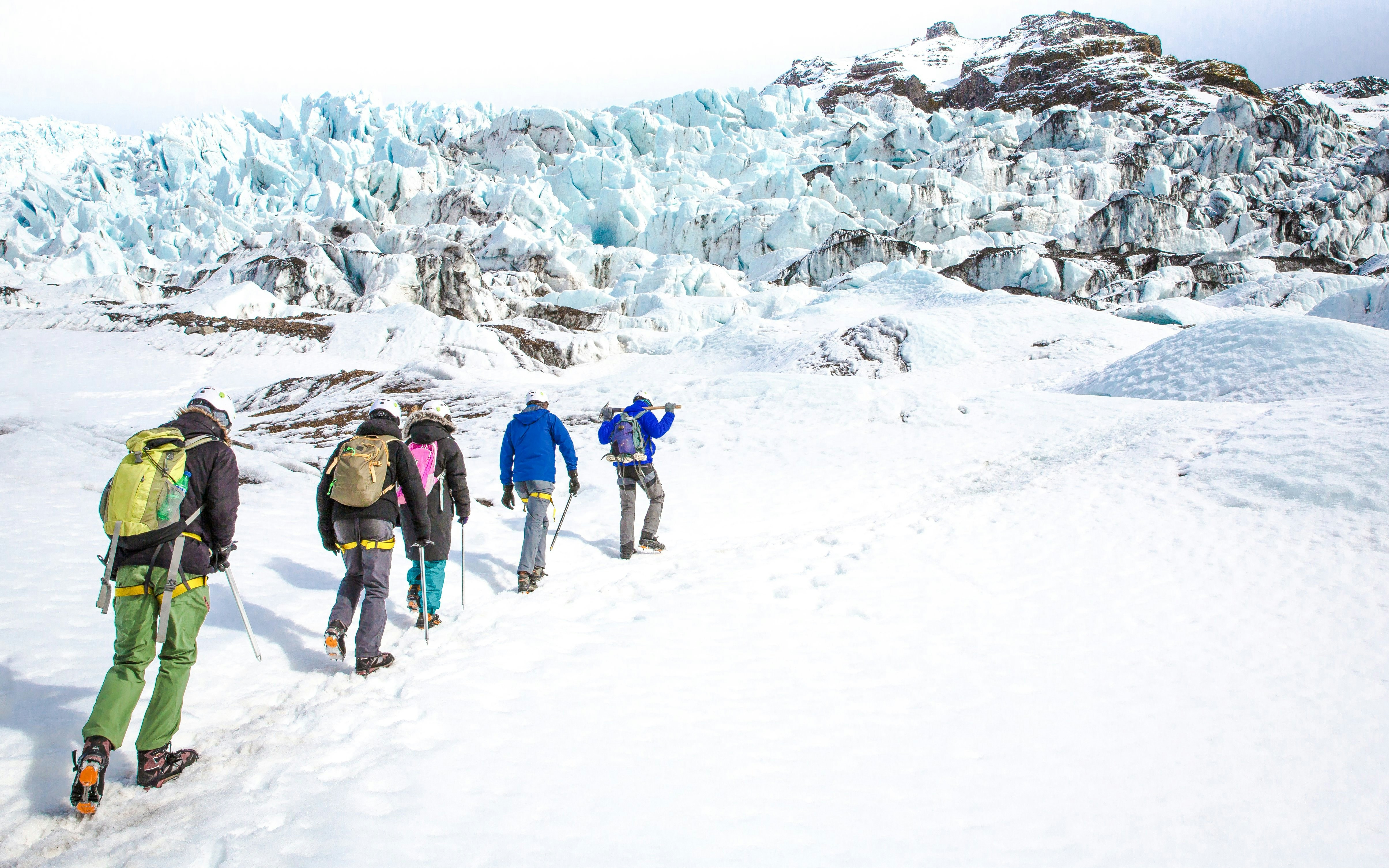 Group hiking on an Icelandic glacier with ice formations in the background.