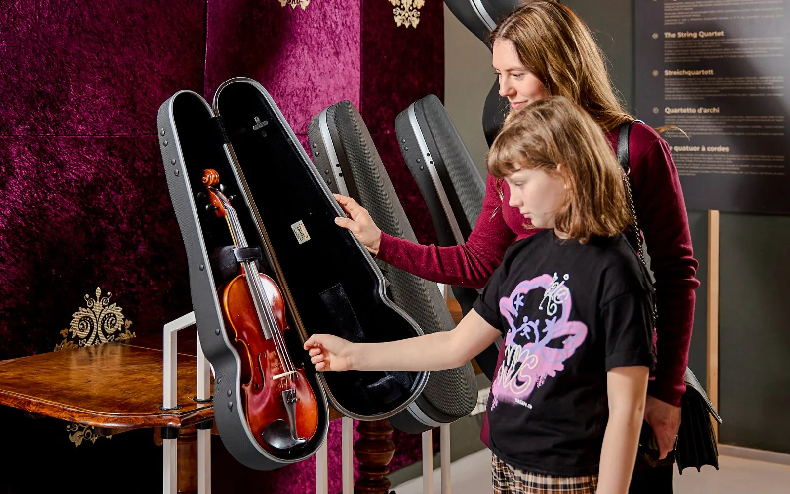 Guests examining a violin exhibit at Mozart Interactive Museum in Prague.