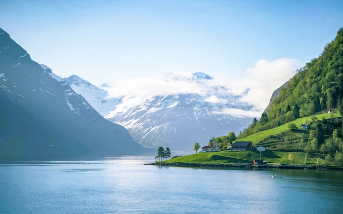 Fjord view with snow-capped mountains and green hills on Ålesund-Geiranger-Ålesund tour.