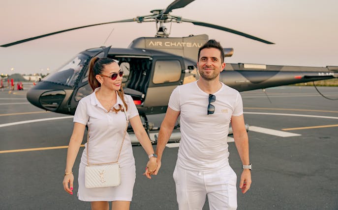 Couple walking near helicopter on tarmac during tour with return transfer.