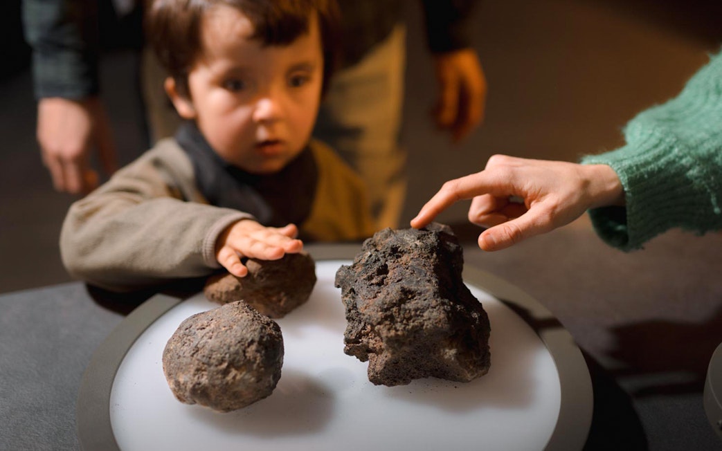 Child exploring volcanic rocks at Espai Crater exhibit.
