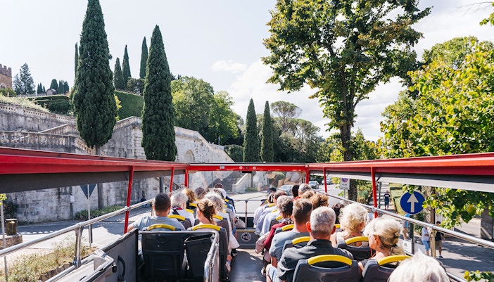 Tourists enjoying the City Sightseeing 24/48/72-Hr Hop-On Hop-Off Tour of Florence, Italy, with a view of the city's historic architecture and landmarks
