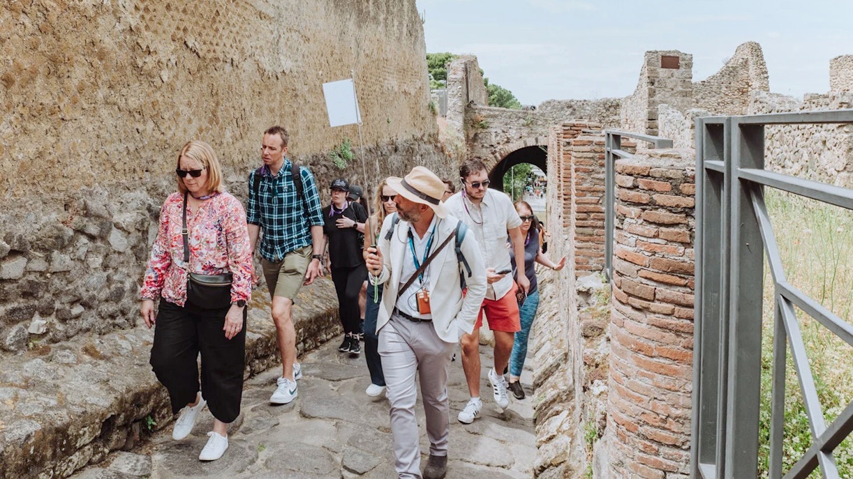 Visitors on a guided tour walking through ancient ruins in Pompeii.
