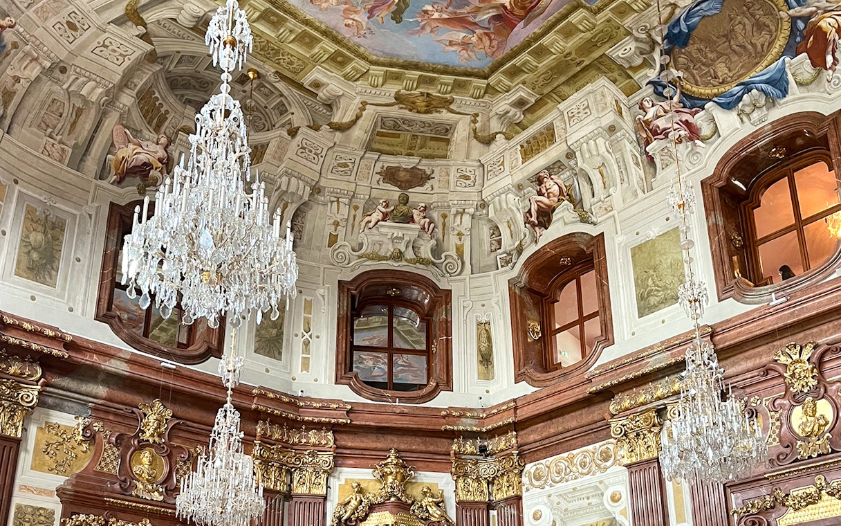 Marble hall interior with chandeliers and ornate ceiling in Belvedere Palace, Vienna.