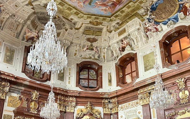 Marble hall interior with chandeliers and ornate ceiling in Belvedere Palace, Vienna.