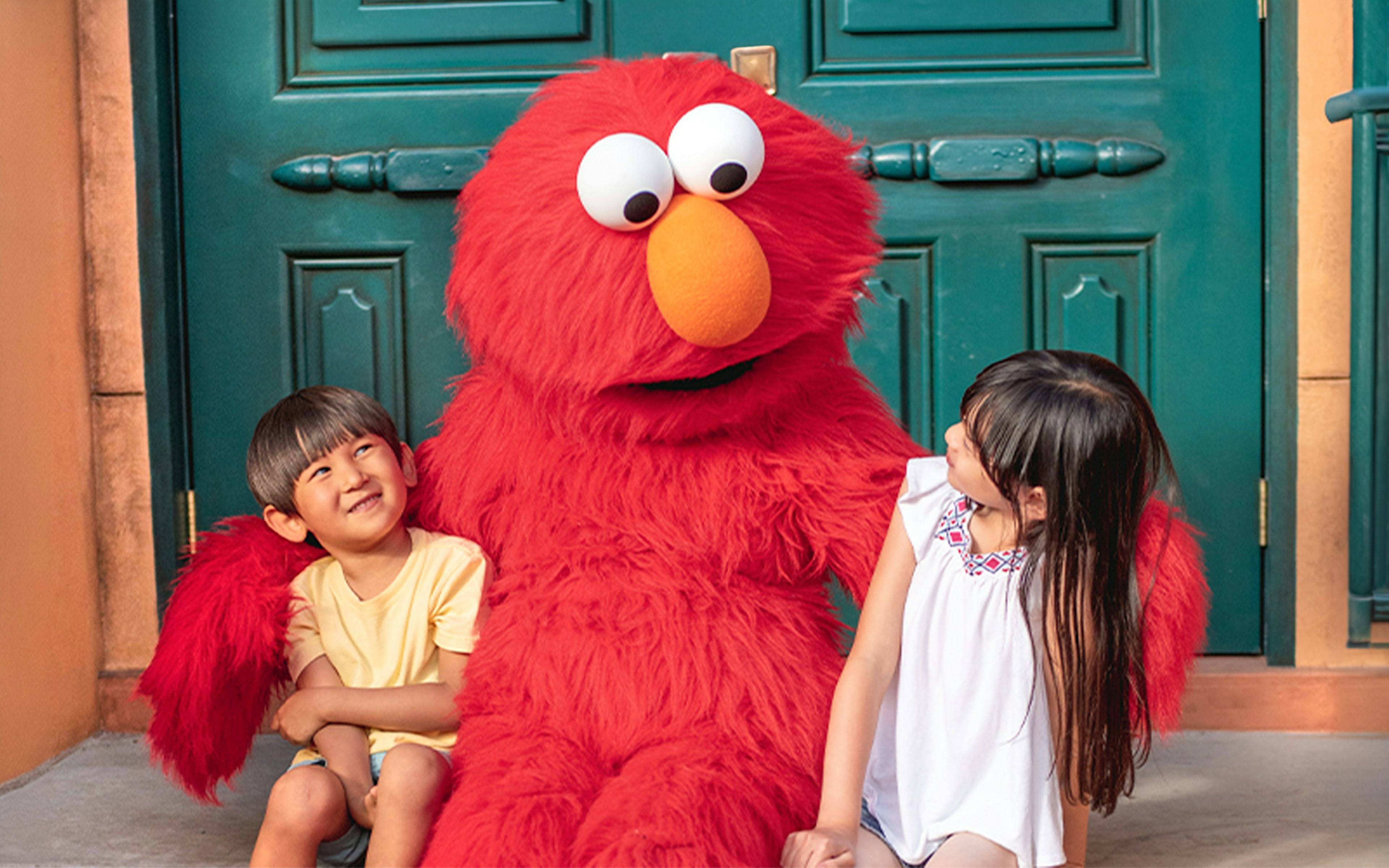 Children sitting with a red furry character at Sesame Place San Diego.