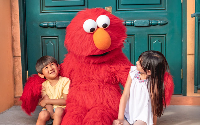 Children sitting with a red furry character at Sesame Place San Diego.