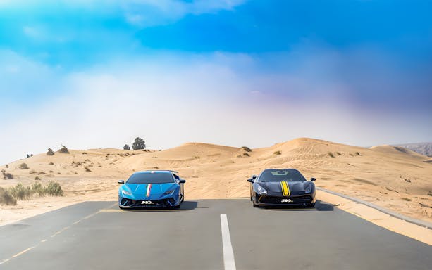 Supercars parked on a desert road in Dubai for a self-drive tour experience.