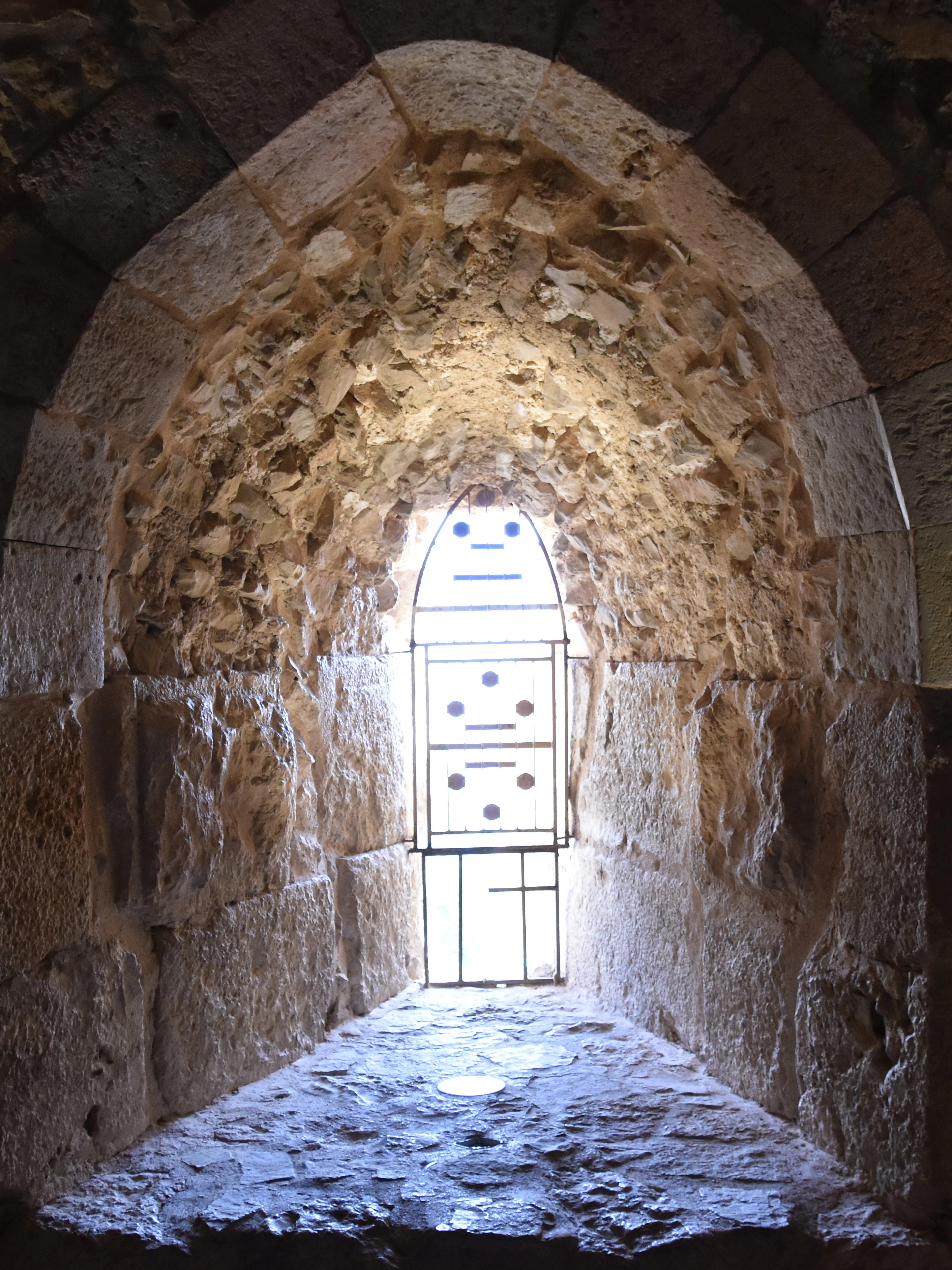 Vaulted stone window frame at Ajloun Castle, Jordan, with intricate arabesque design.