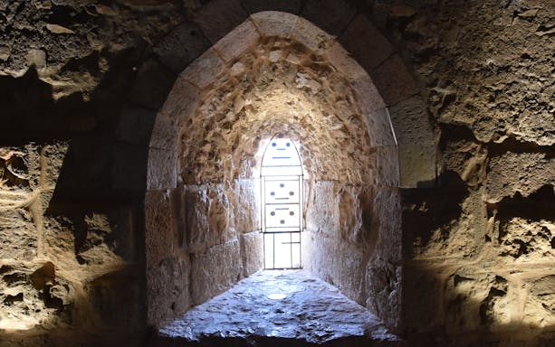Vaulted stone window frame at Ajloun Castle, Jordan, with intricate arabesque design.