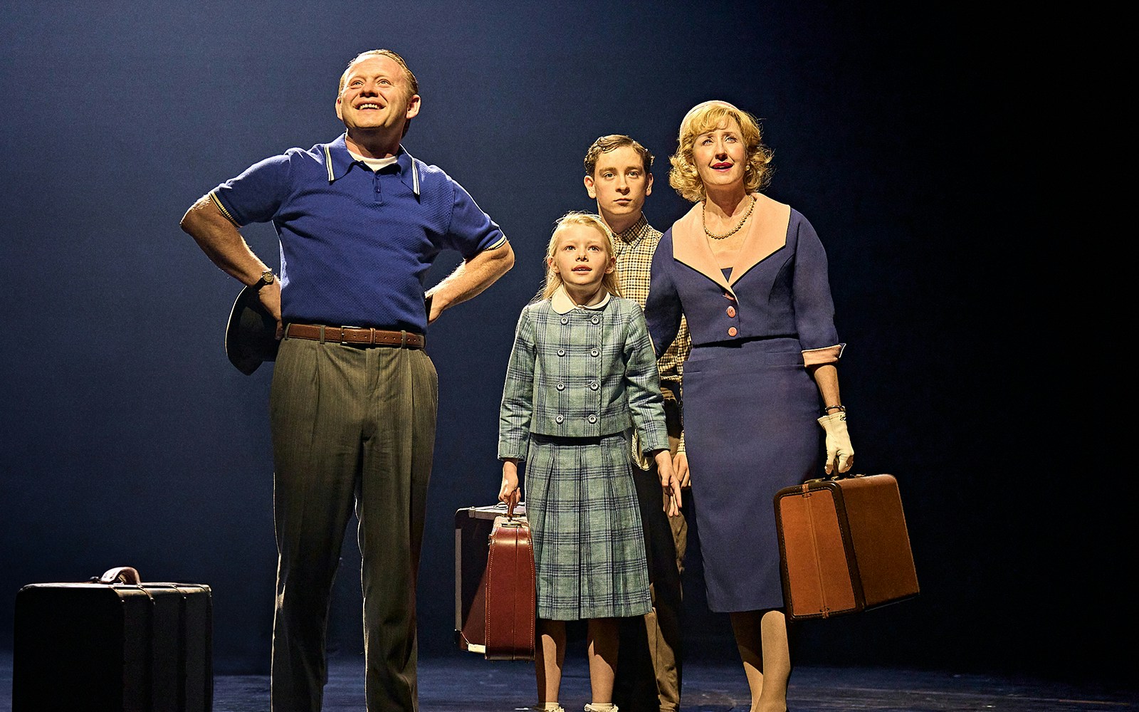 Family with suitcases on stage in "Stranger Things: The First Shadow" performance.